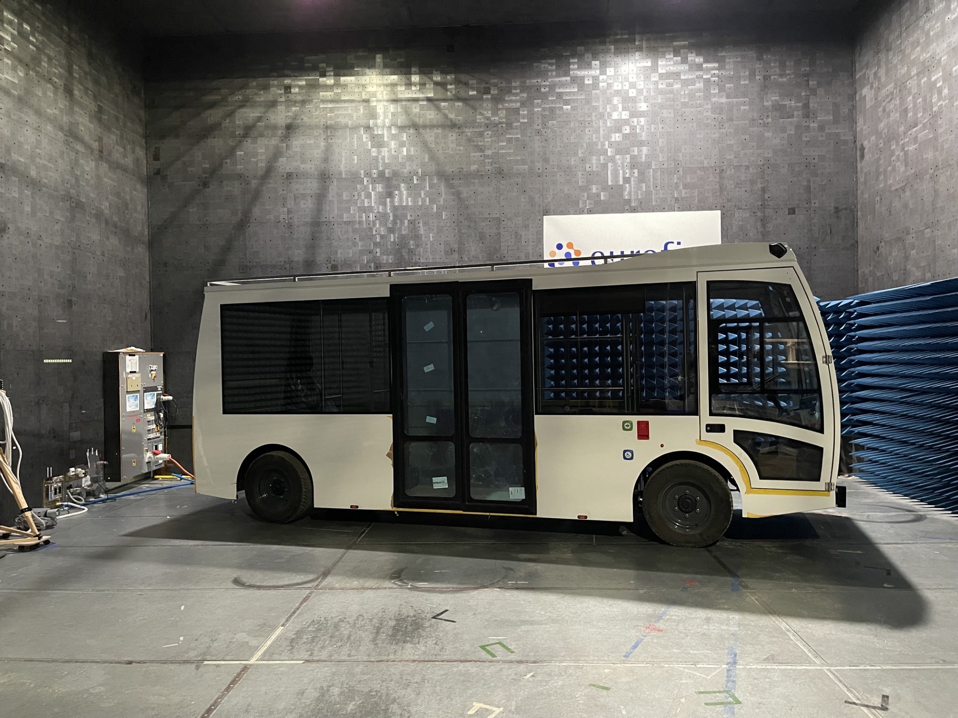 Electric shuttle bus undergoing EMC testing inside a Eurofins anechoic chamber lined with RF-absorbing foam