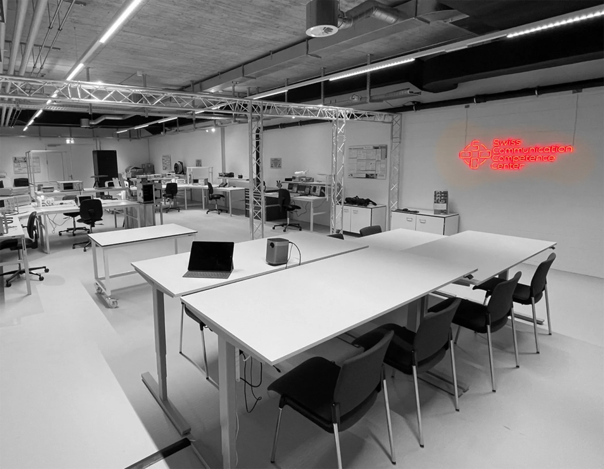 The Swiss Communication Competence Center laboratory with test benches, instruments and the SCCC neon sign